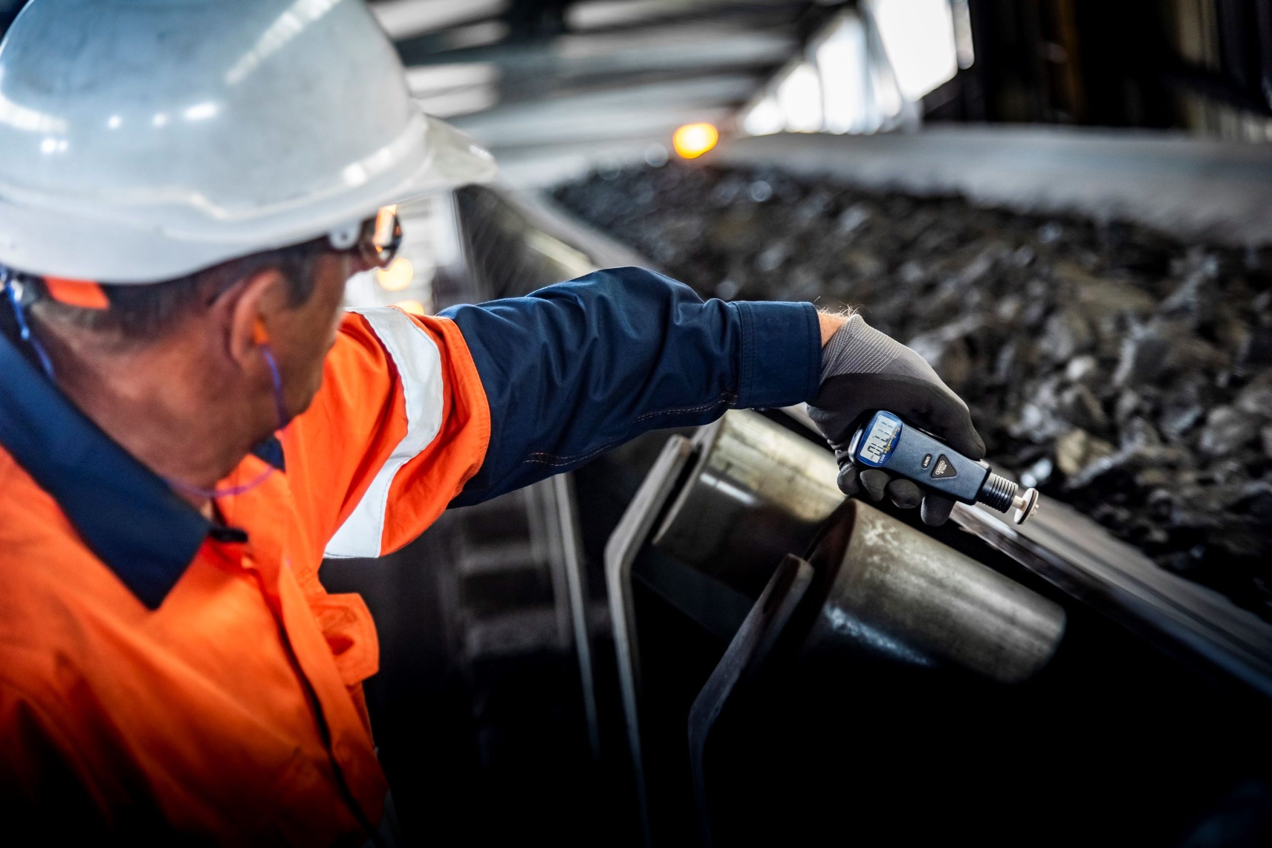 A technical advisor from Weba Chute Systems measures belt speed to ensure optimal material flow and minimal impact on the transfer chute.