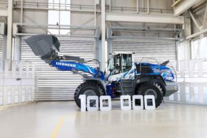 The ‘100 000’ lettering, composed of historical black-and-white images, traces the development of Liebherr wheel loaders.