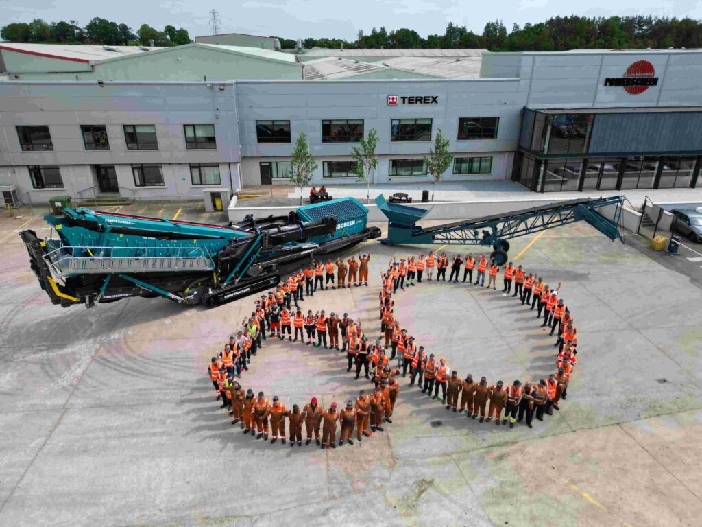 Employees gather in the shape of a giant ‘60’ alongside two Powerscreen machines (one current model, one original model).