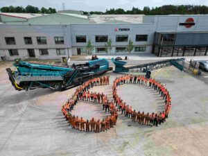 Employees gather in the shape of a giant ‘60’ alongside two Powerscreen machines (one current model, one original model).